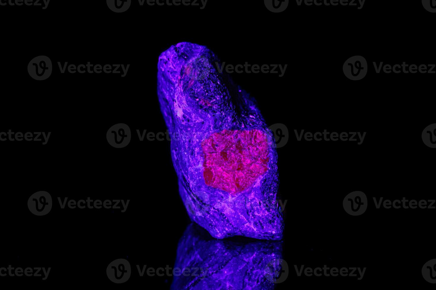 macro mineral stone ruby under ultraviolet light on a black background photo