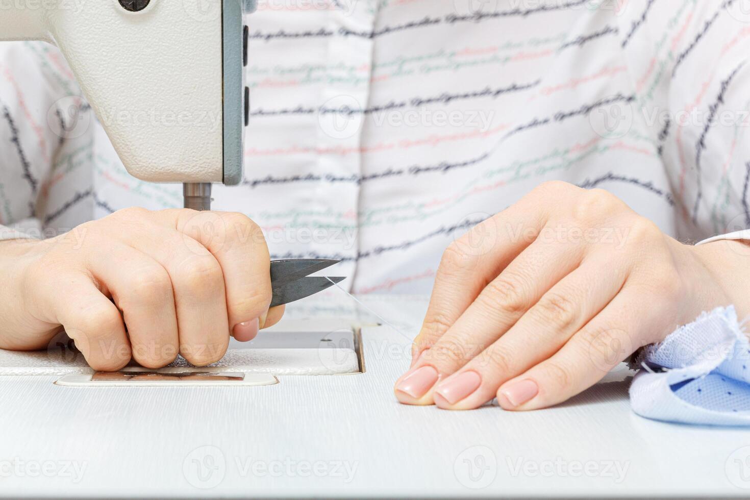 Female hands of a master tailor cuts a thread with scissors photo