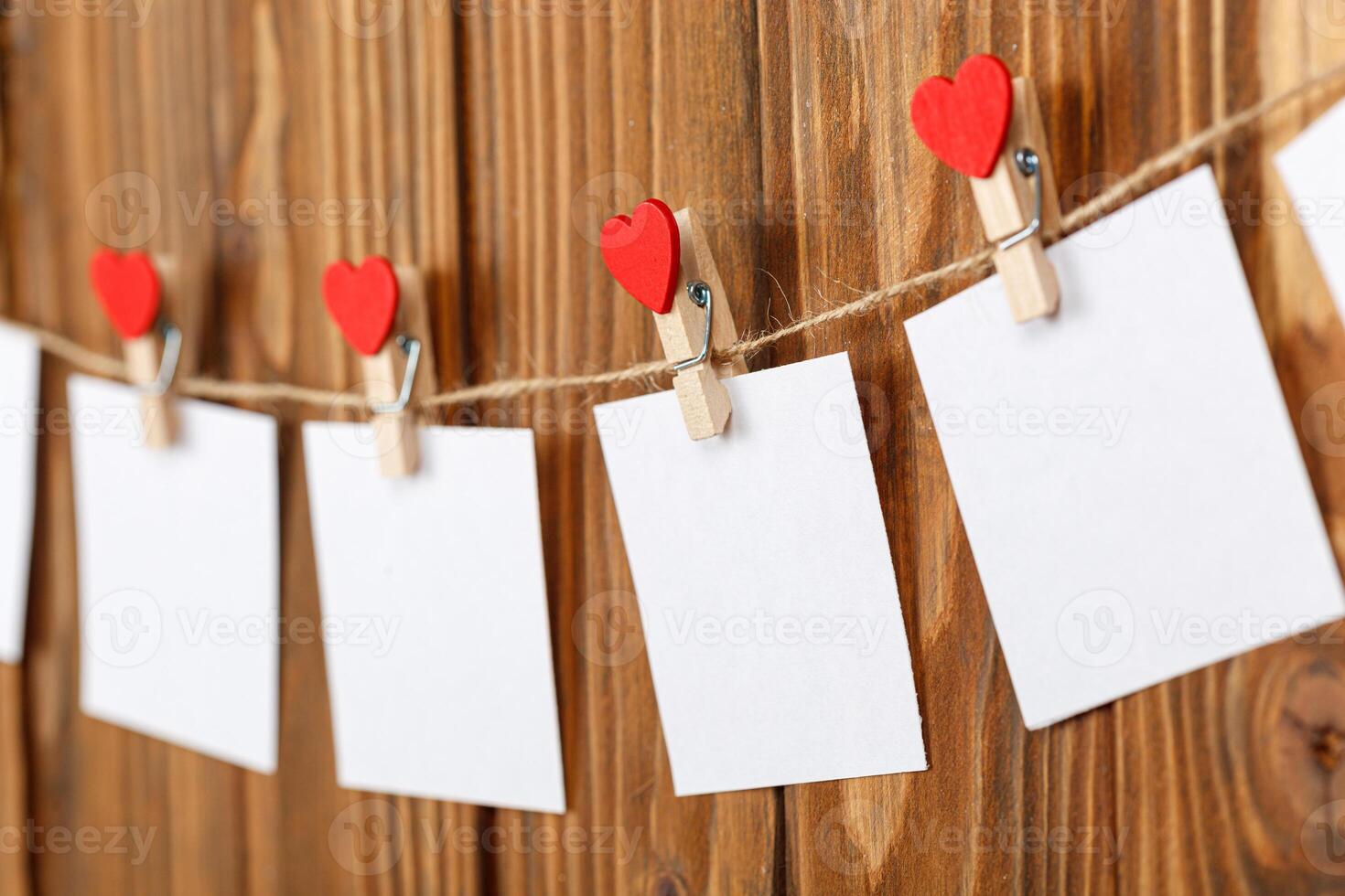 white pieces of paper on clothespins with a heart on a wooden background photo