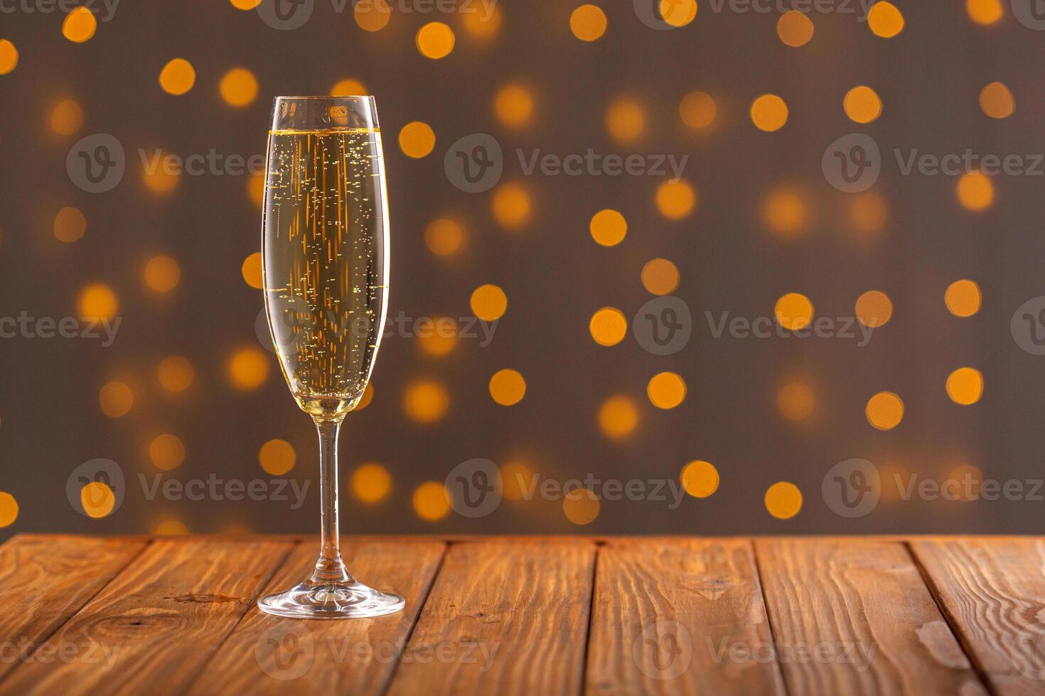 Glasses with champagne on a wooden background against a bokeh background of lights photo