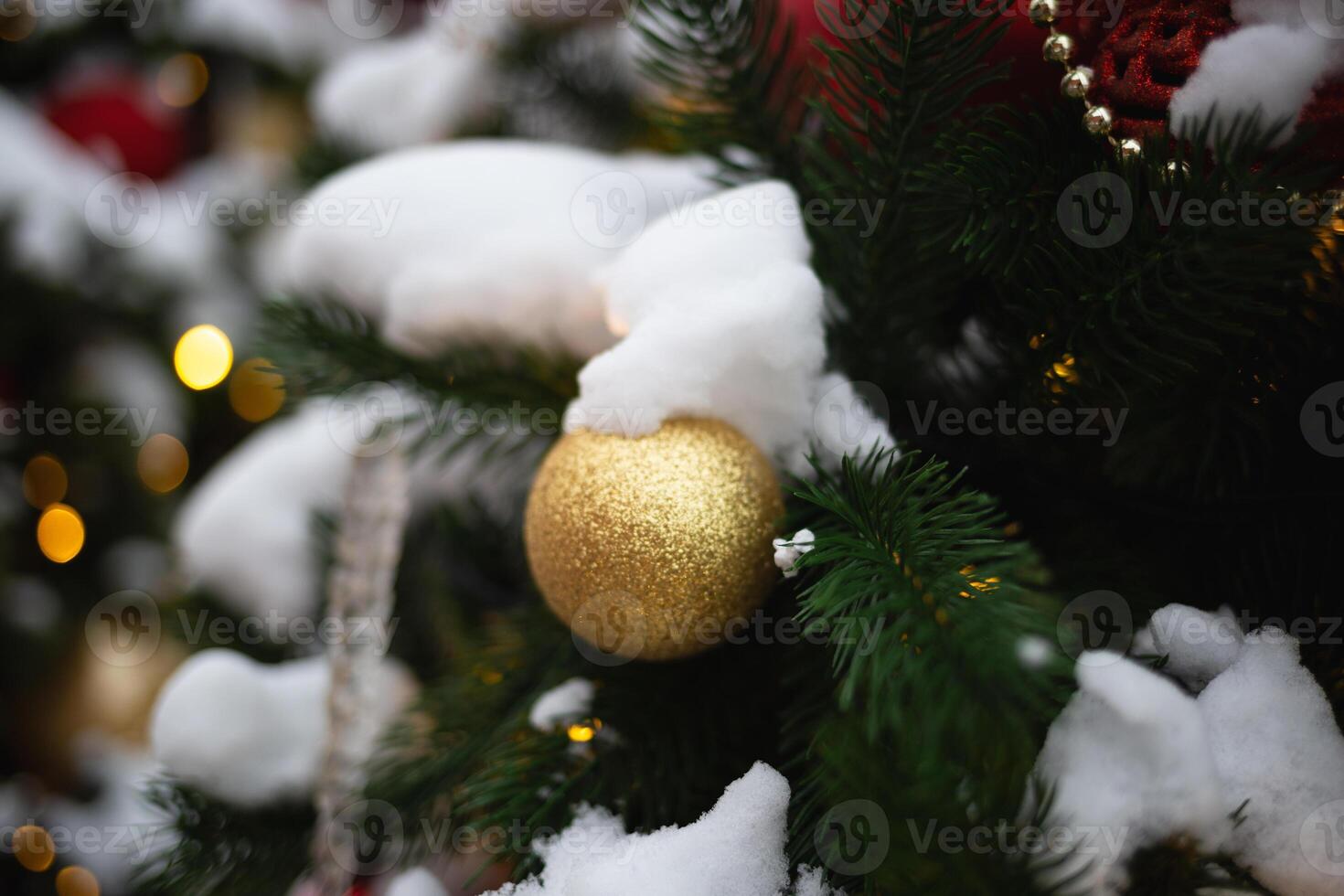 beautiful multi-colored toys on a Christmas tree against the background of lights and snow photo