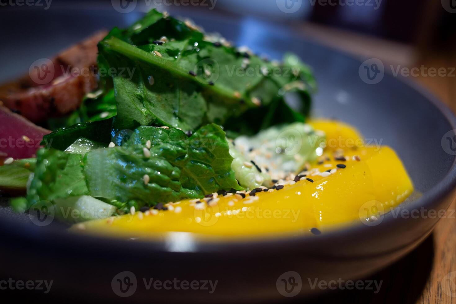 fresh bright juicy tuna and mango salad with spinach on a beautiful gray plate photo