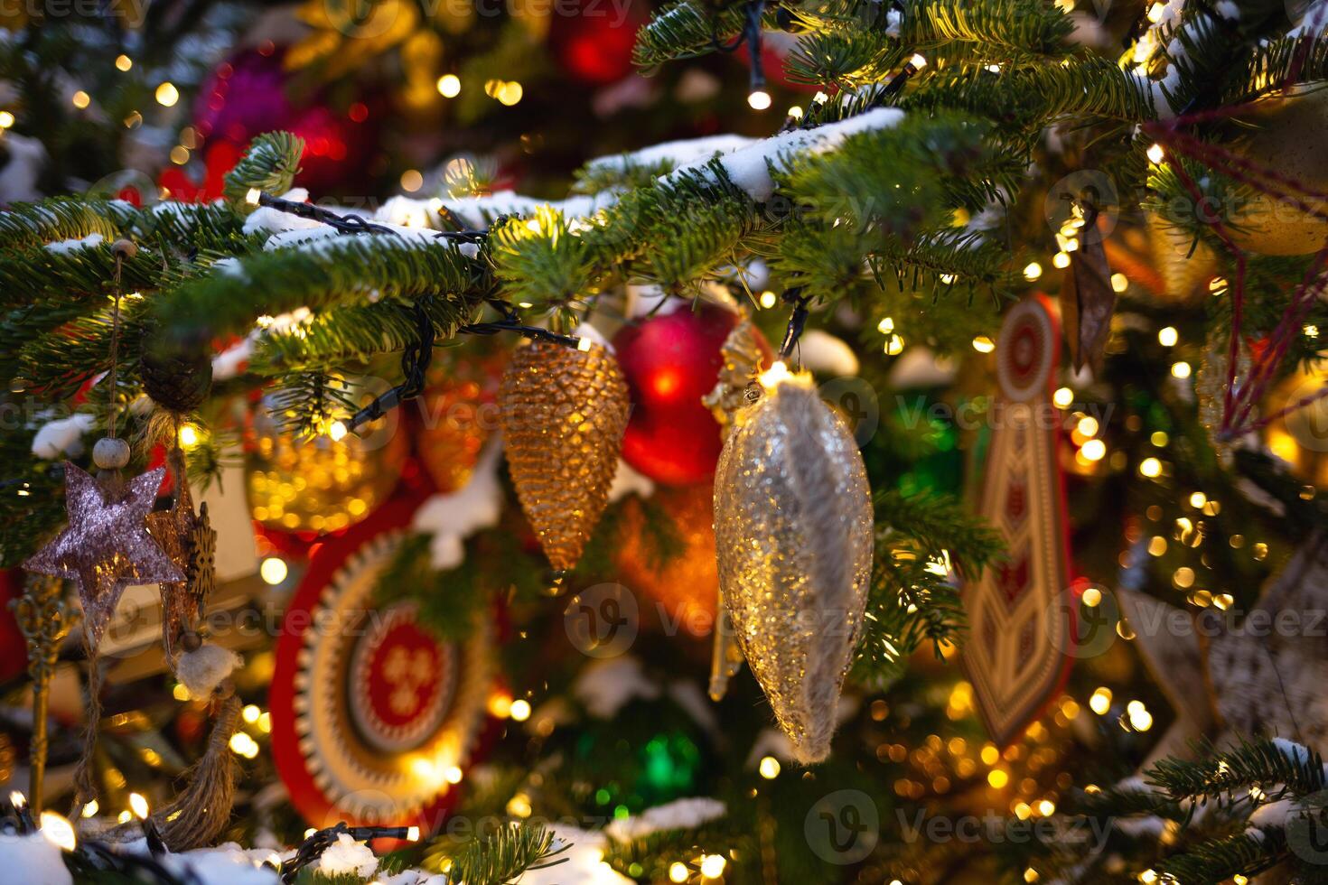 beautiful multi-colored toys on a Christmas tree against the background of lights and snow photo
