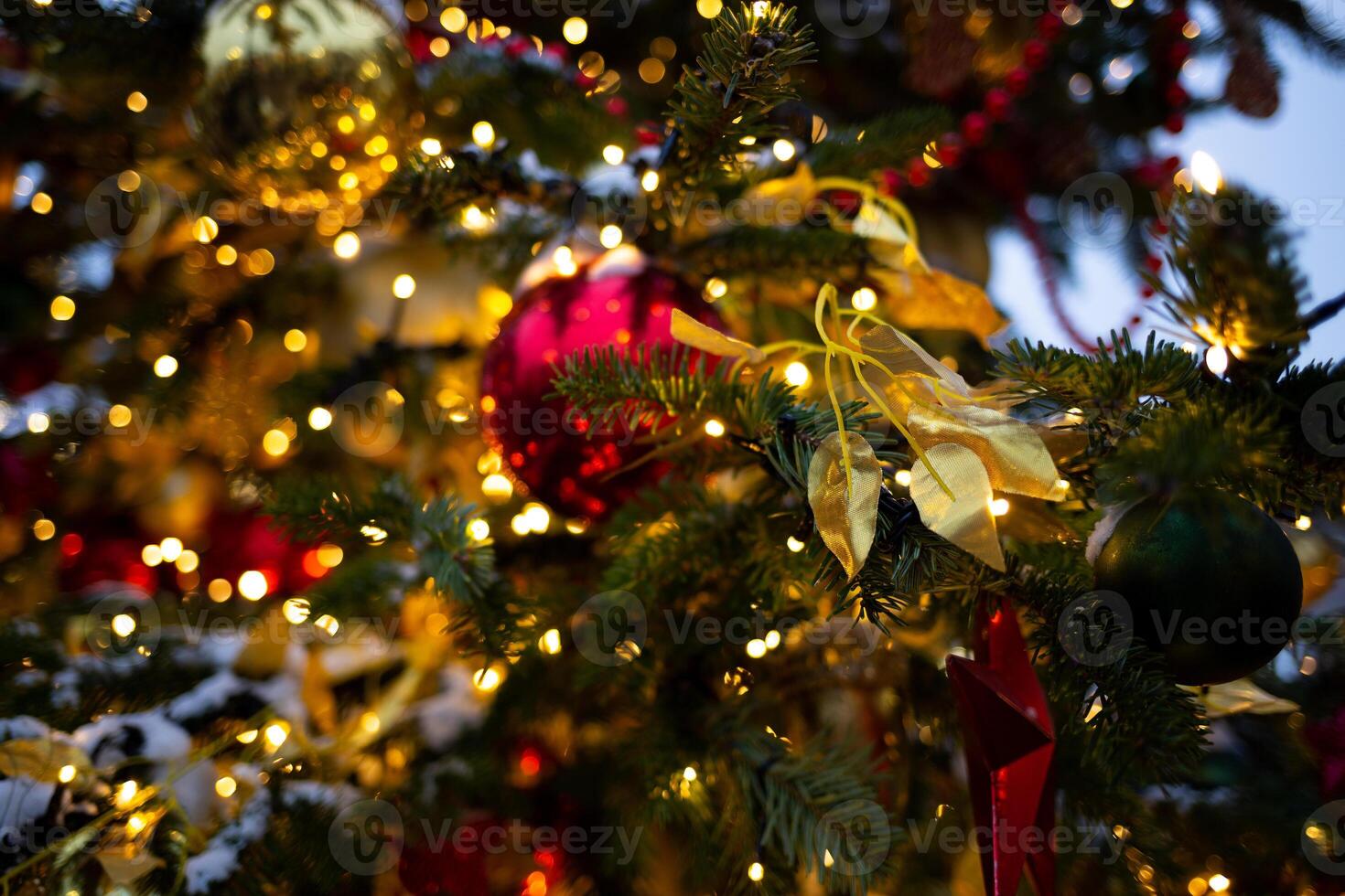 beautiful multi-colored toys on a Christmas tree against the background of lights and snow photo