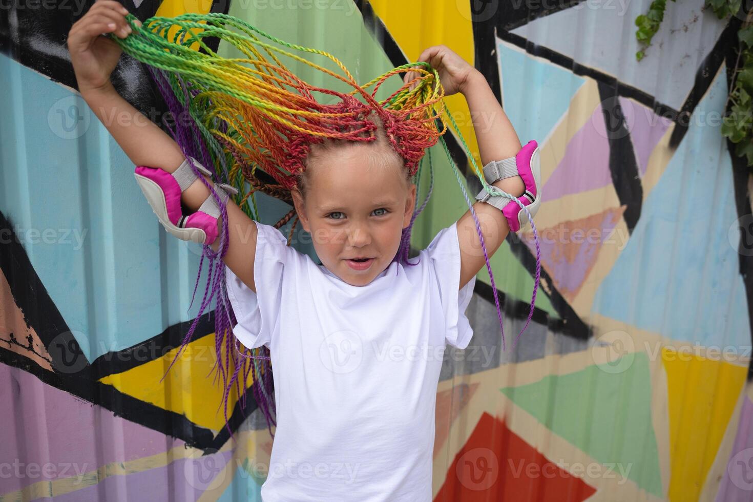 girl with multi-colored african braids on the background of a colorful wall photo