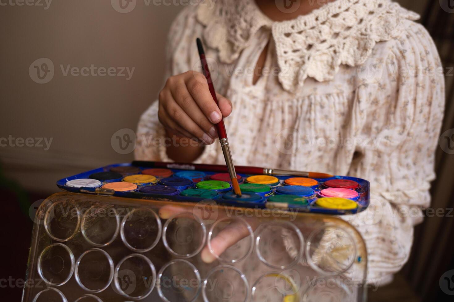 little cute girl draws with paints on canvas at the easel. photo