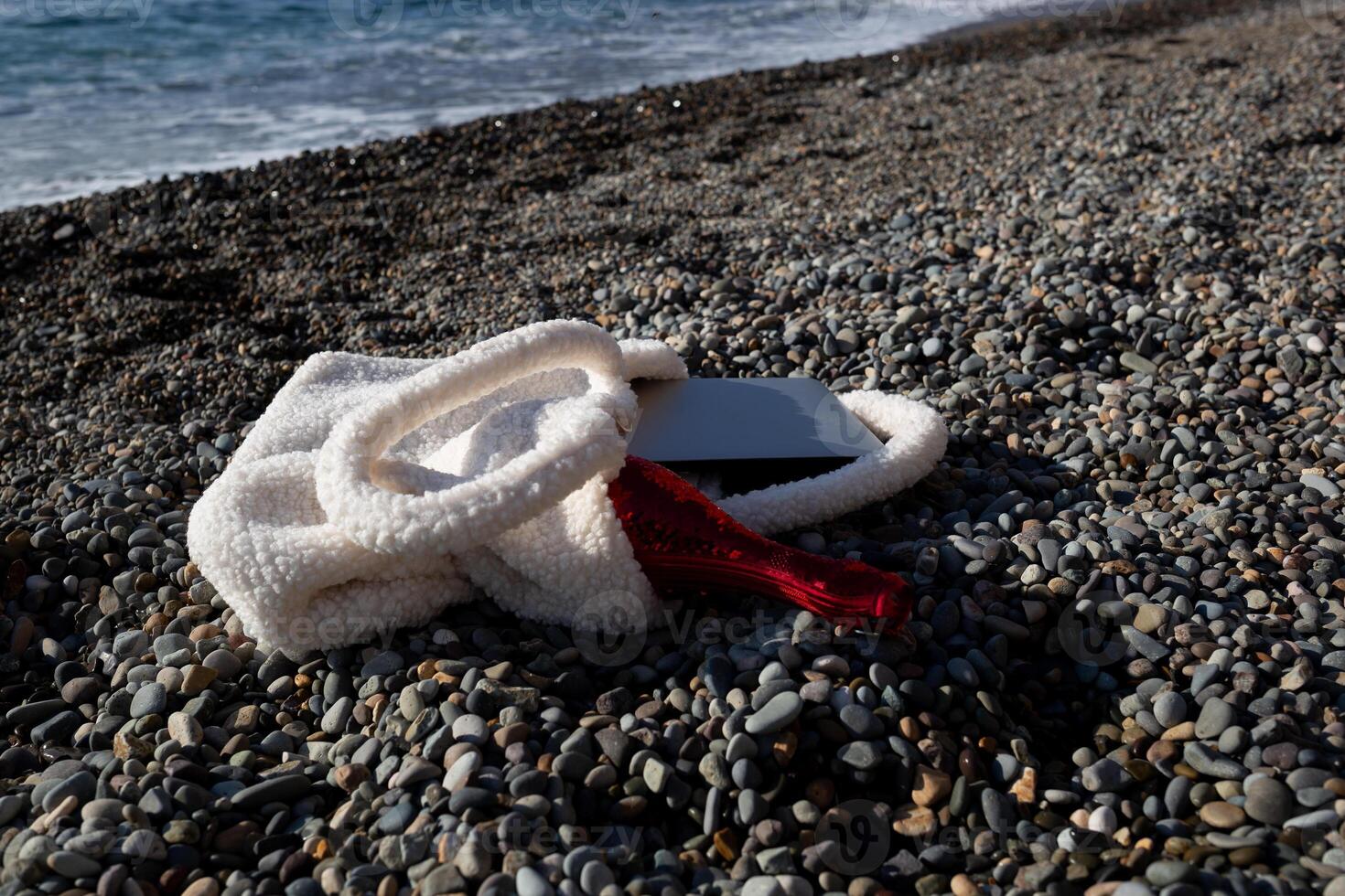 a bag with a laptop and a bottle of champagne lies on the coast of the sea photo