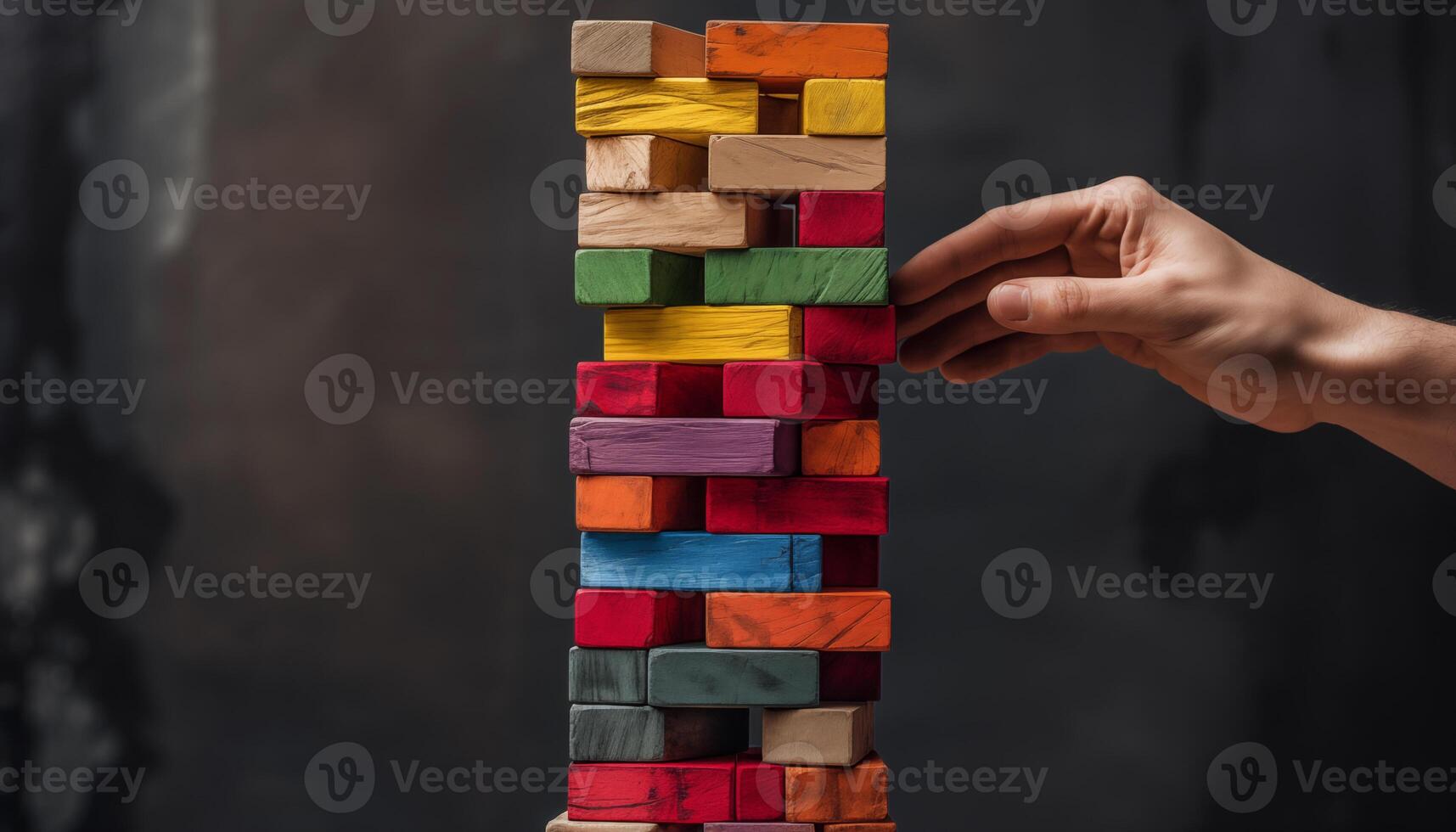 side view of Hand pulling colorful wooden block from the tower photo