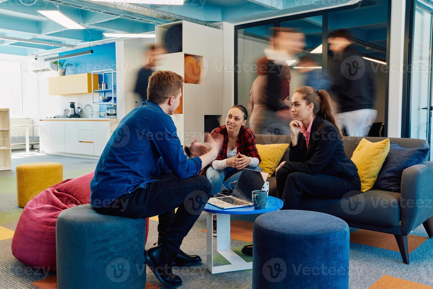 Multiethnic startup business team on meeting in a modern bright open space coworking office. Brainstorming, working on laptop. Group of coworkers walking around in motion blur photo
