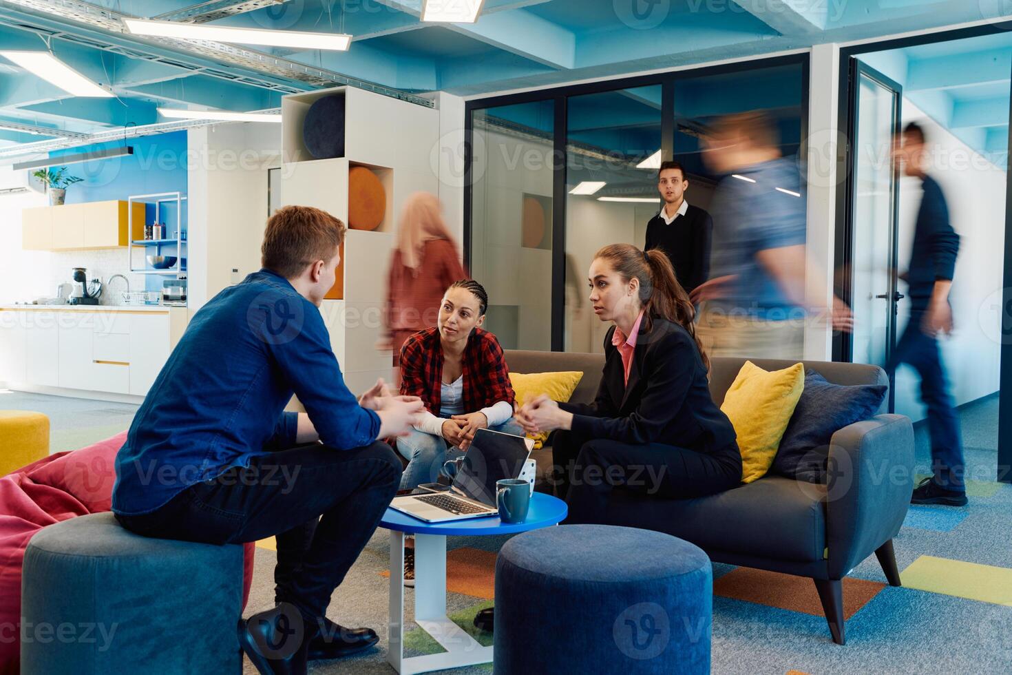 Multiethnic startup business team on meeting in a modern bright open space coworking office. Brainstorming, working on laptop. Group of coworkers walking around in motion blur photo