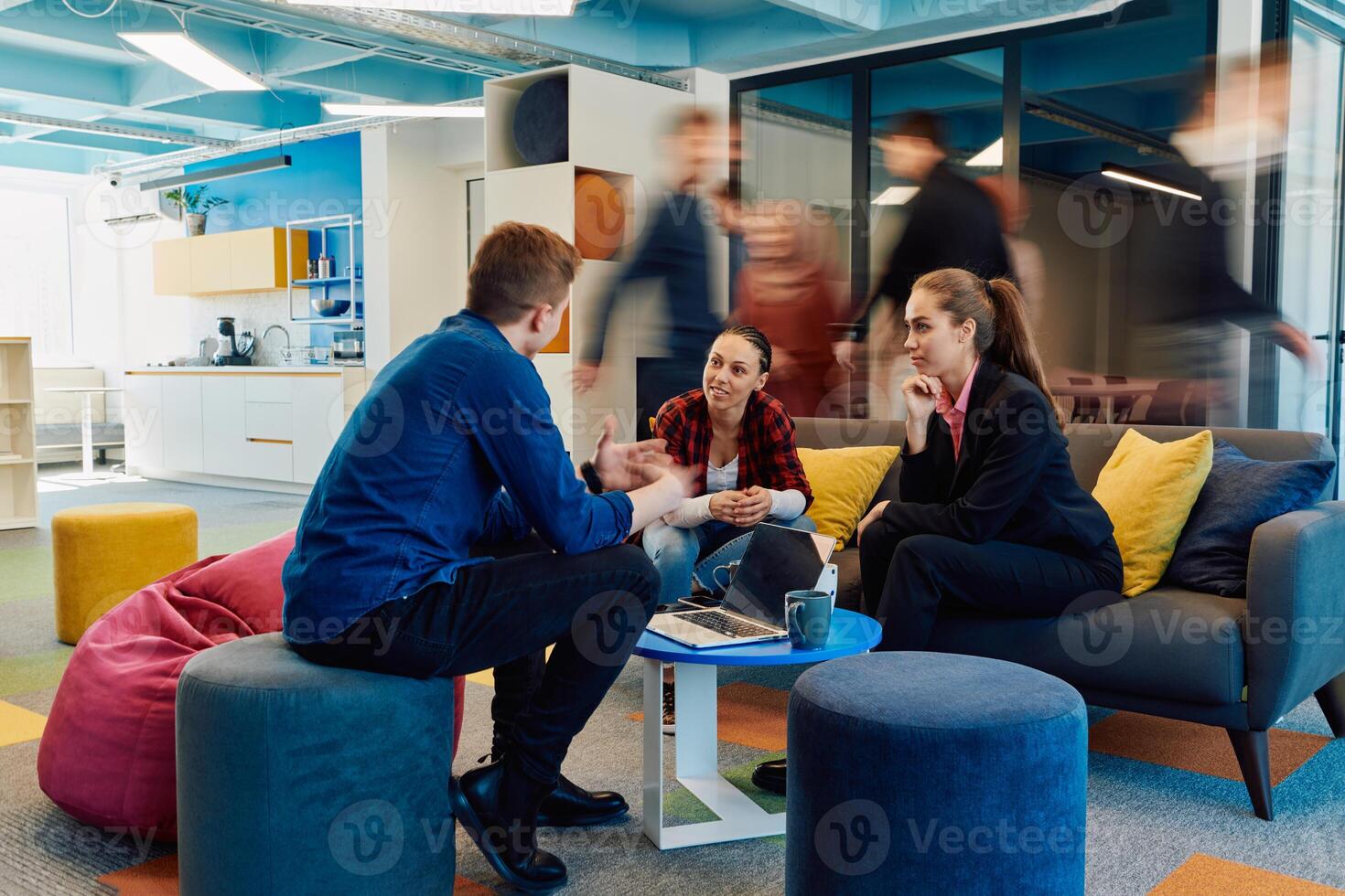 Multiethnic startup business team on meeting in a modern bright open space coworking office. Brainstorming, working on laptop. Group of coworkers walking around in motion blur photo