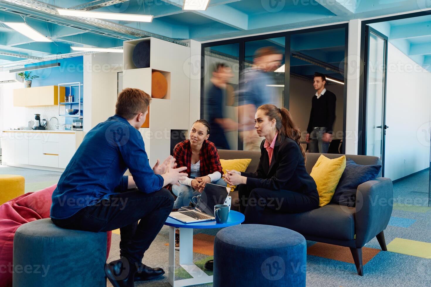 Multiethnic startup business team on meeting in a modern bright open space coworking office. Brainstorming, working on laptop. Group of coworkers walking around in motion blur photo