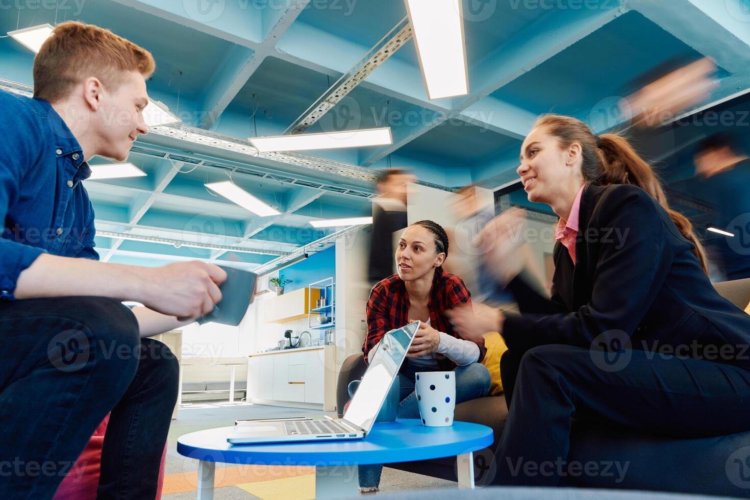 Multiethnic startup business team on meeting in a modern bright open space coworking office. Brainstorming, working on laptop. Group of coworkers walking around in motion blur photo