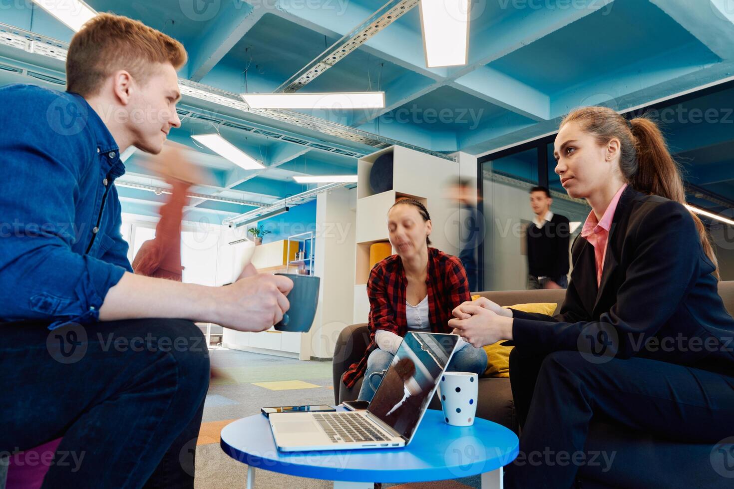 Multiethnic startup business team on meeting in a modern bright open space coworking office. Brainstorming, working on laptop. Group of coworkers walking around in motion blur photo