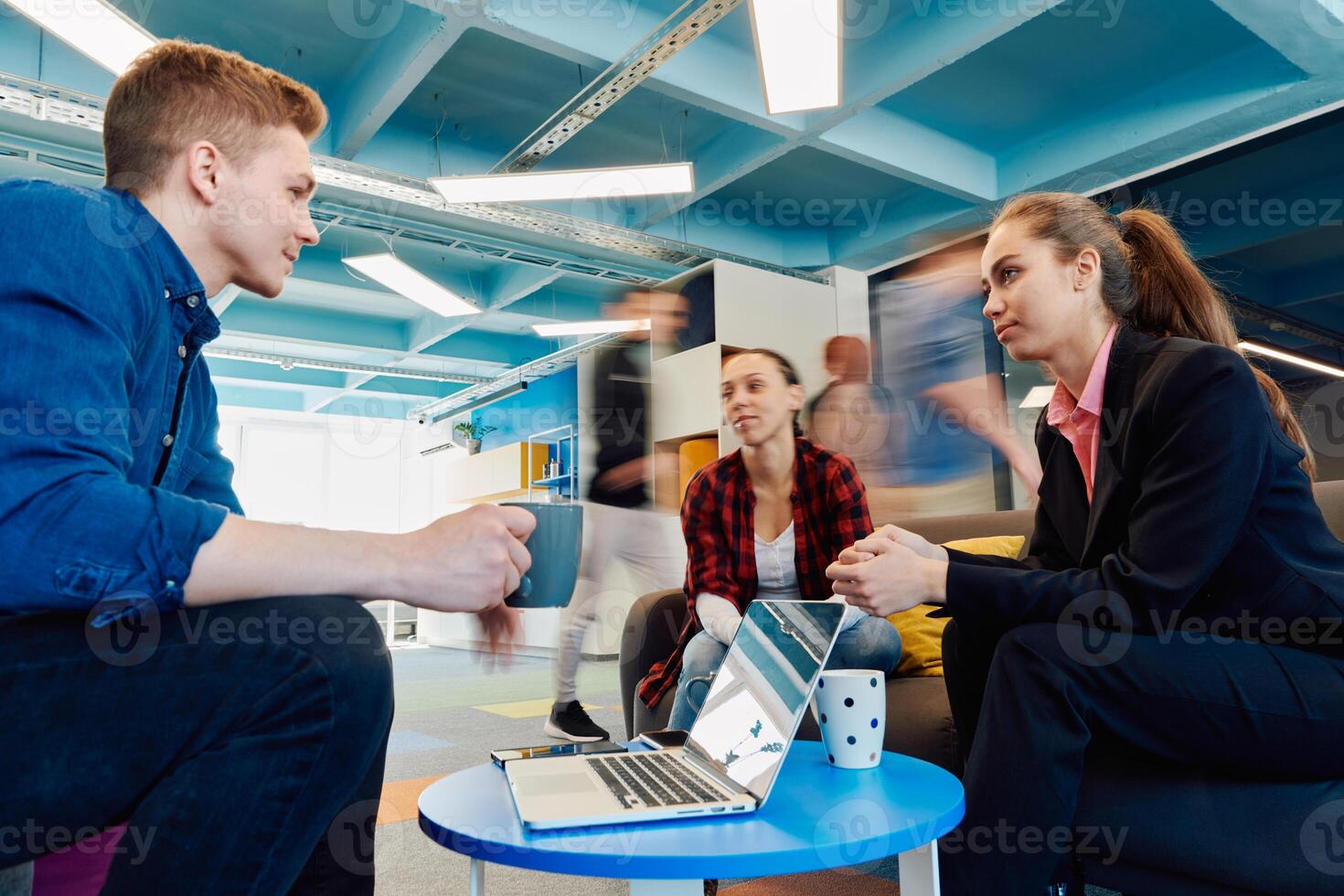 Multiethnic startup business team on meeting in a modern bright open space coworking office. Brainstorming, working on laptop. Group of coworkers walking around in motion blur photo