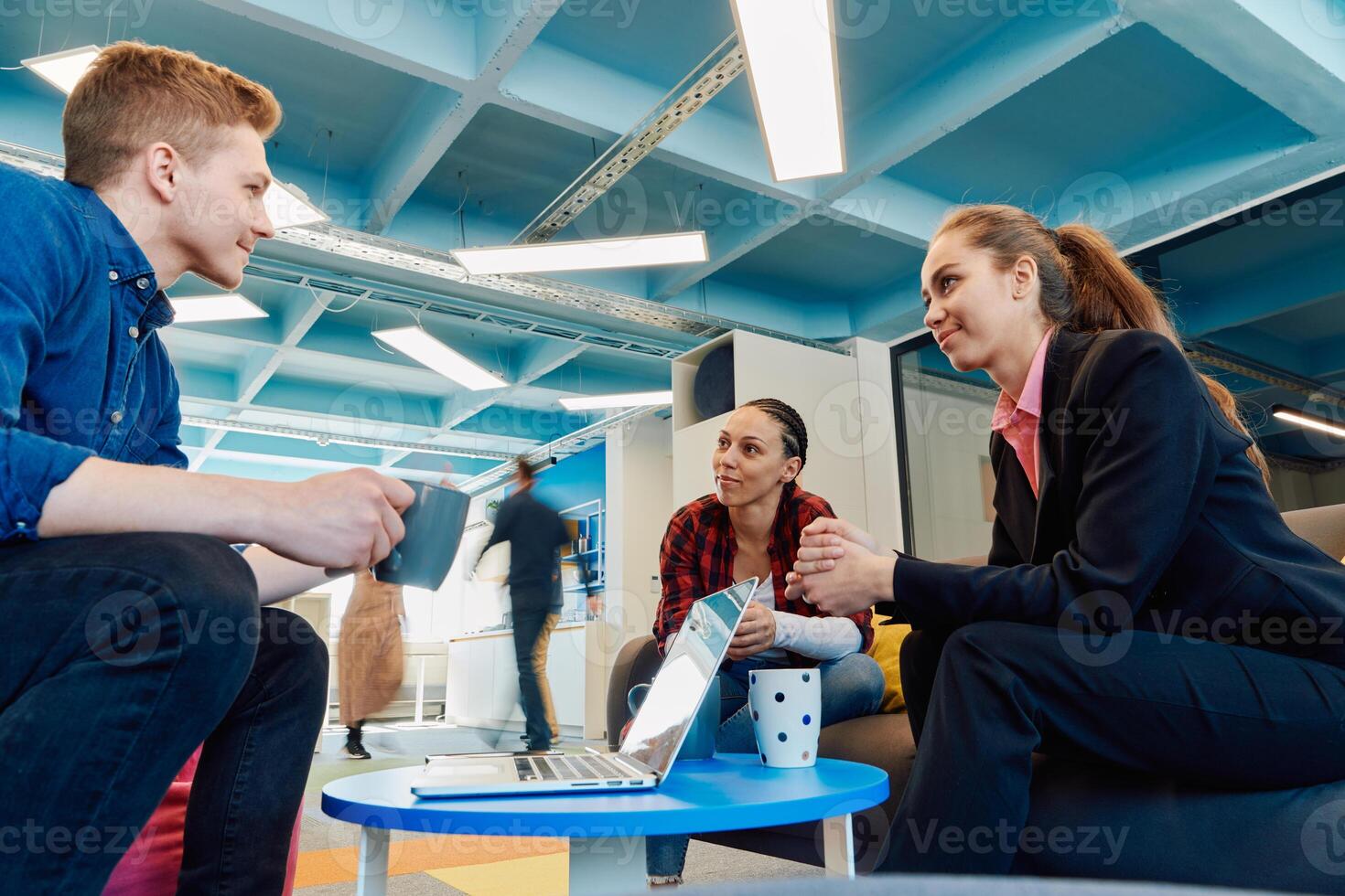 Multiethnic startup business team on meeting in a modern bright open space coworking office. Brainstorming, working on laptop. Group of coworkers walking around in motion blur photo