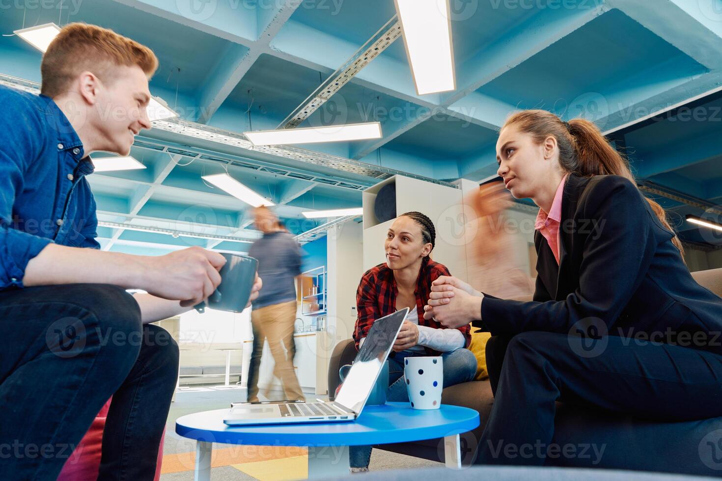 Multiethnic startup business team on meeting in a modern bright open space coworking office. Brainstorming, working on laptop. Group of coworkers walking around in motion blur photo