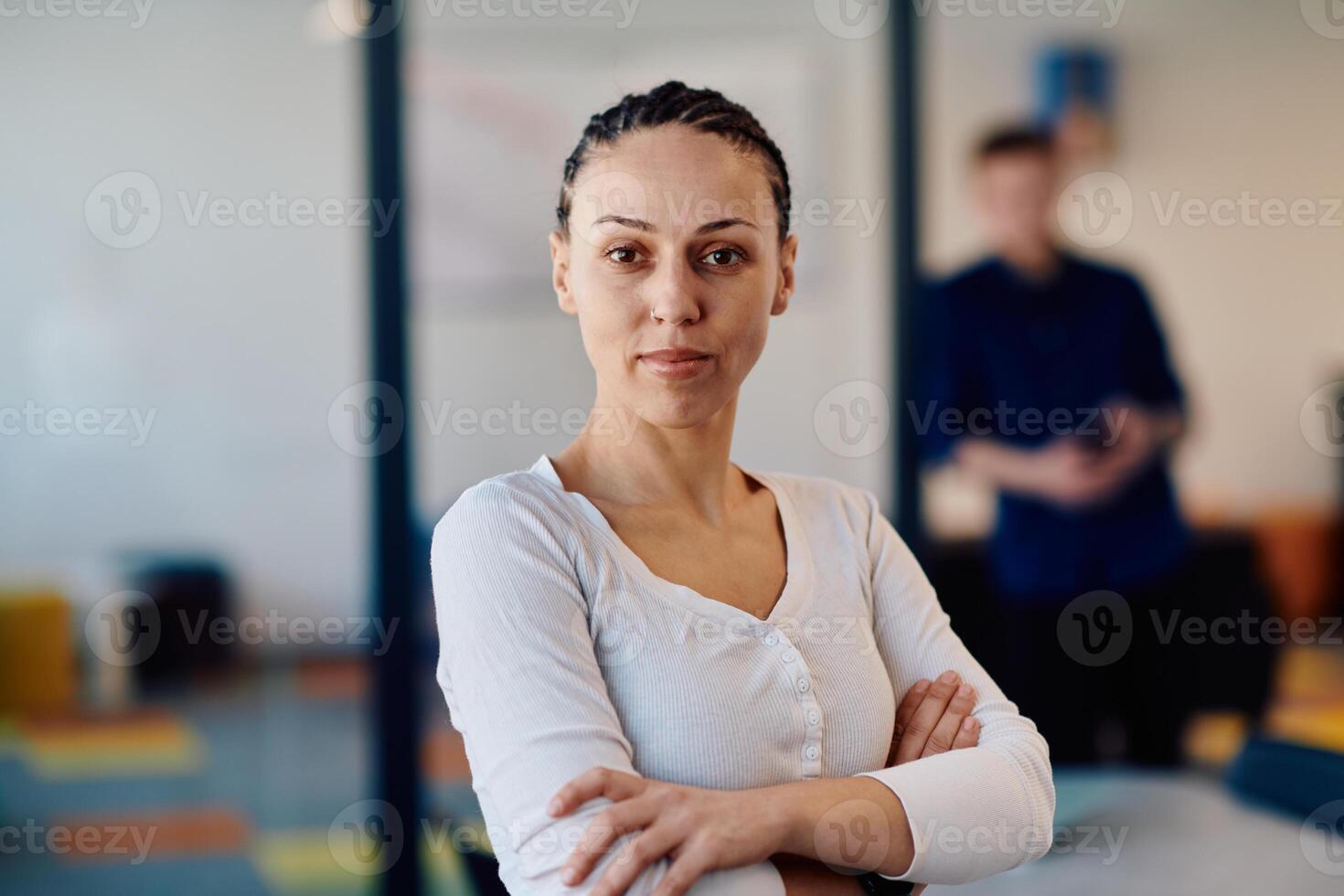 Portrait of a business woman in a creative open space coworking startup office with crossed arms. Successful businesswoman standing in office with copyspace. Associates work in the background photo