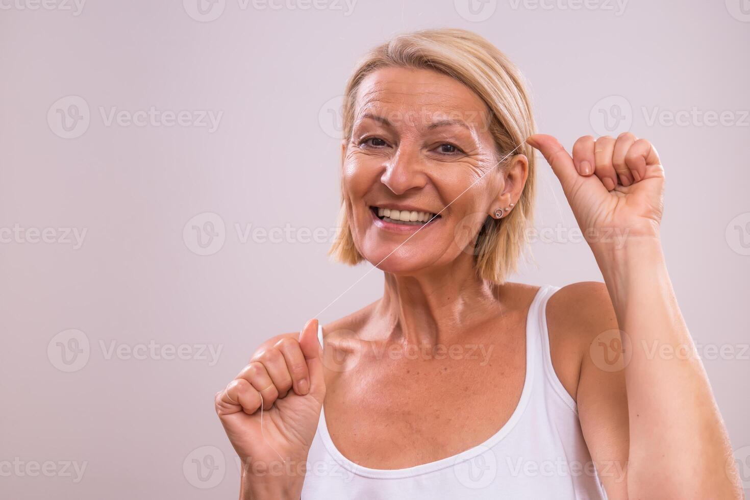 Portrait of beautiful mature woman using dental floss. photo