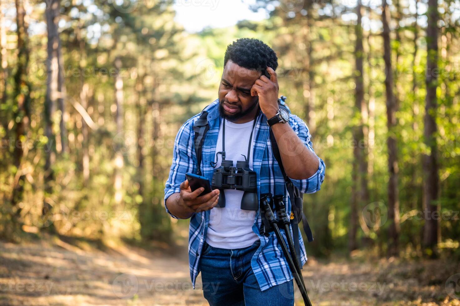 Worried hiker got lost and he is using a phone to find right direction while hiking in the nature. photo