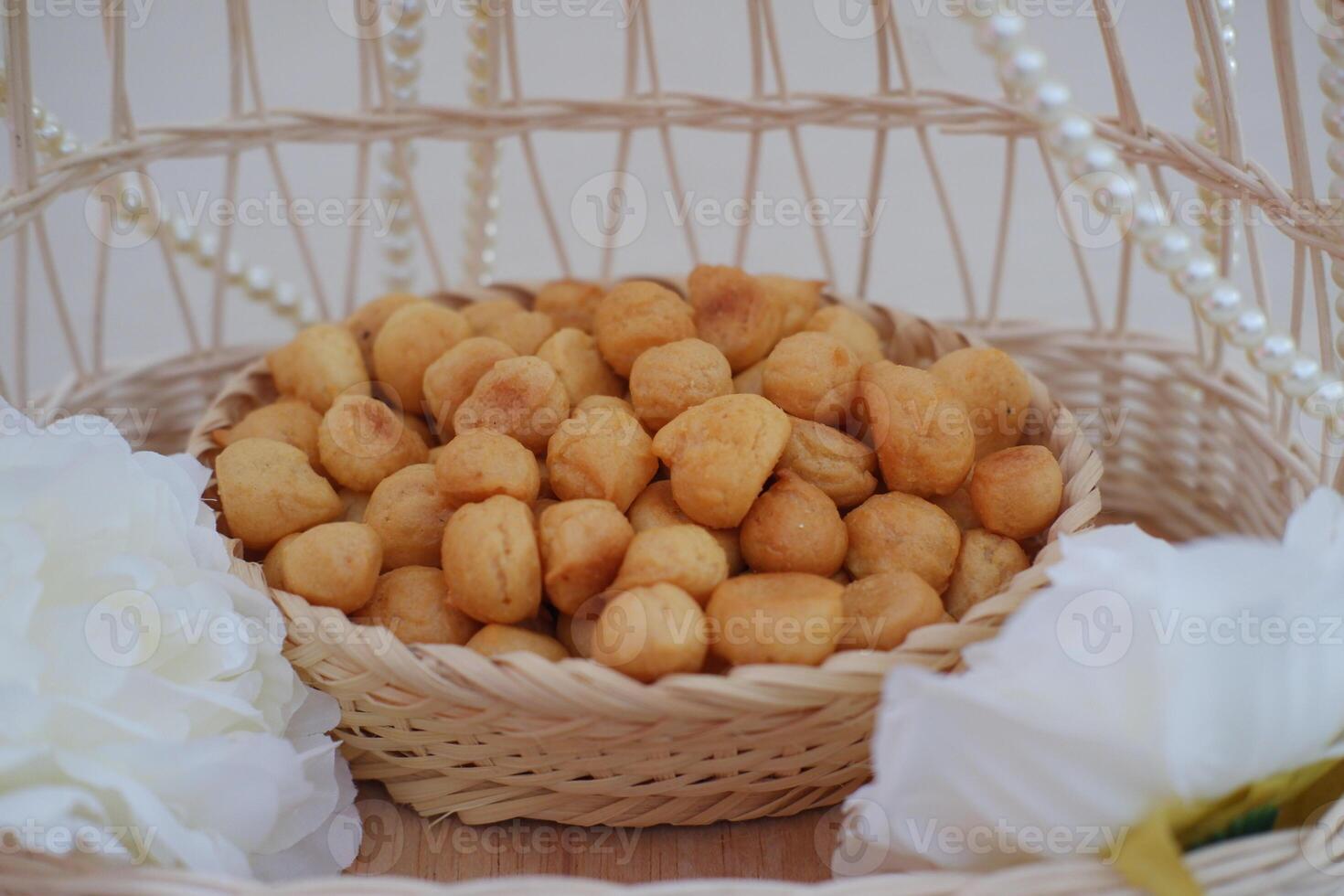 a traditional cake from Indonesia called kue sus filled with cream puffs. served on wooden basket. photo
