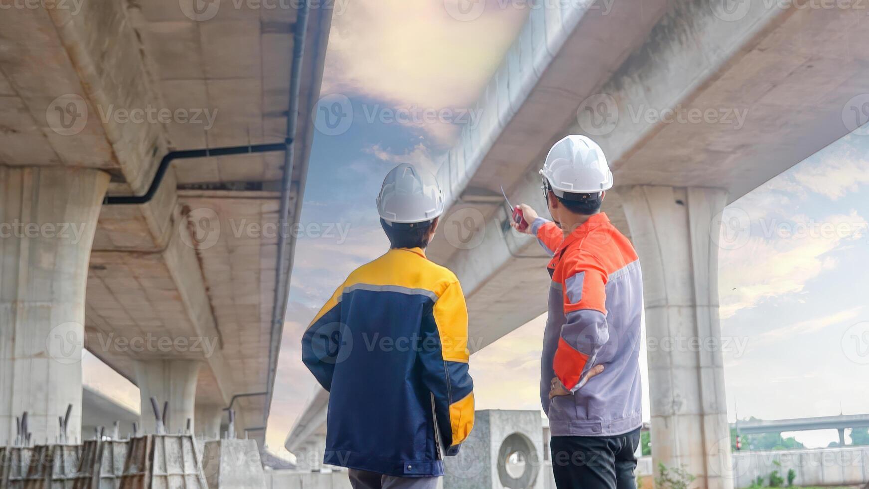 Back view of Asian male and female engineers Inspecting construction work radio command concrete road bridge highway photo