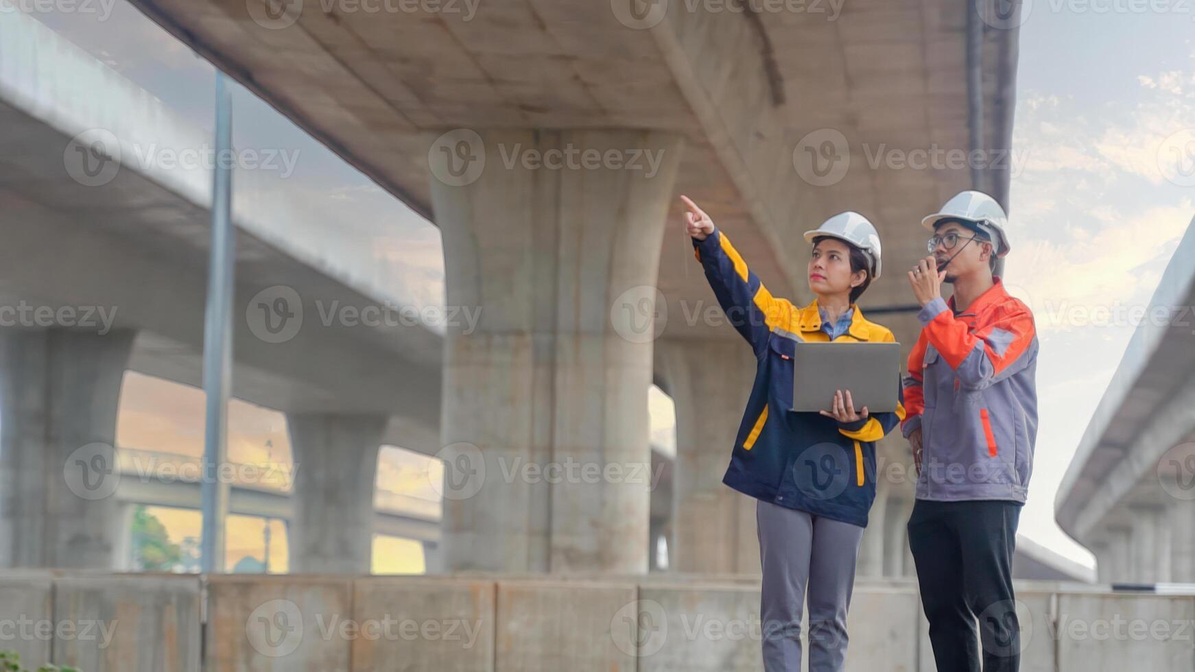 Asian male and female engineers Inspecting construction work radio command concrete road bridge highway photo