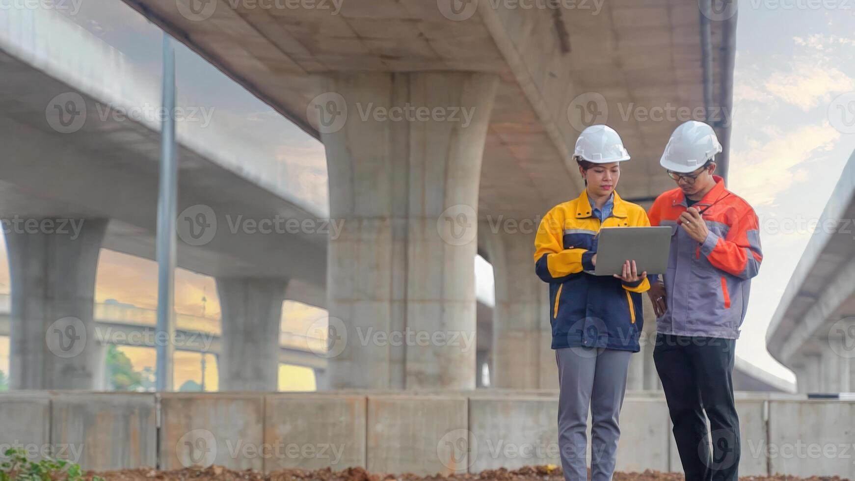 Asian male and female engineers Inspecting construction work radio command concrete road bridge highway photo