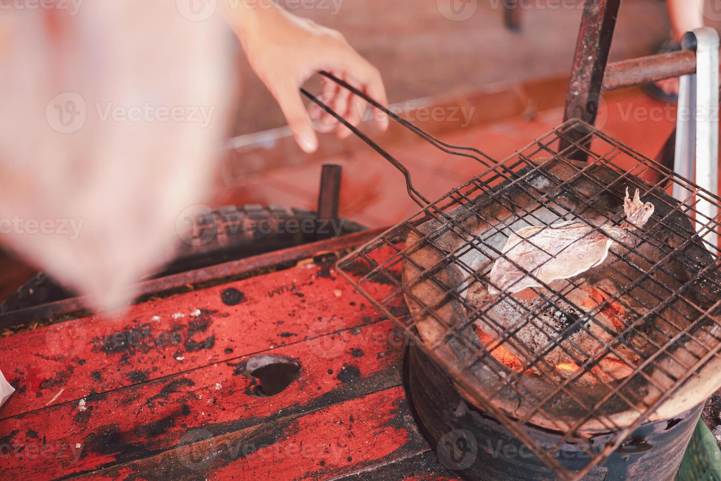 Close up of the vendor is grilling squid grill with dried squids photo