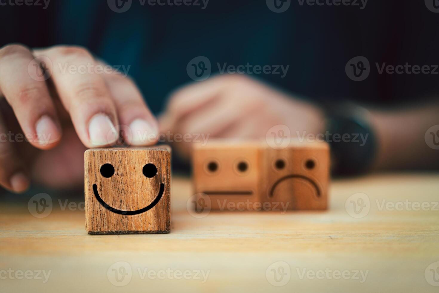 Man hand showing rating with happy icon on dark brown wood block. photo