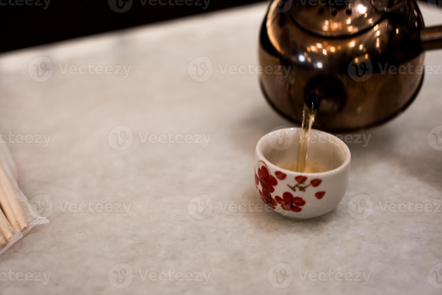 Hand pouring hot tea from teapot photo