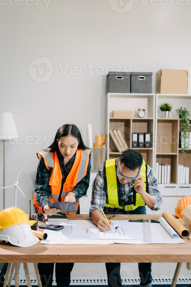 Engineer teams meeting working together wear worker helmets hardhat with on architectural project site and making model house. Asian industry professional team photo