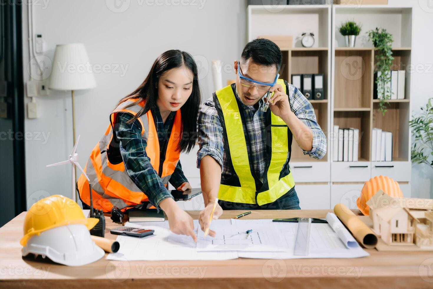 Engineer teams meeting working together wear worker helmets hardhat with on architectural project site and making model house. Asian industry professional team photo