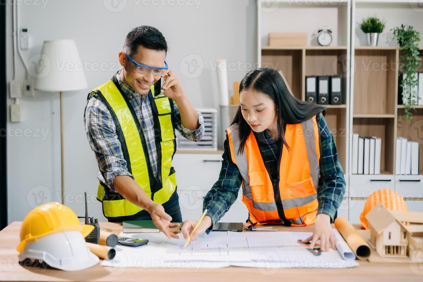 Engineer teams meeting working together wear worker helmets hardhat with on architectural project site and making model house. Asian industry professional team photo