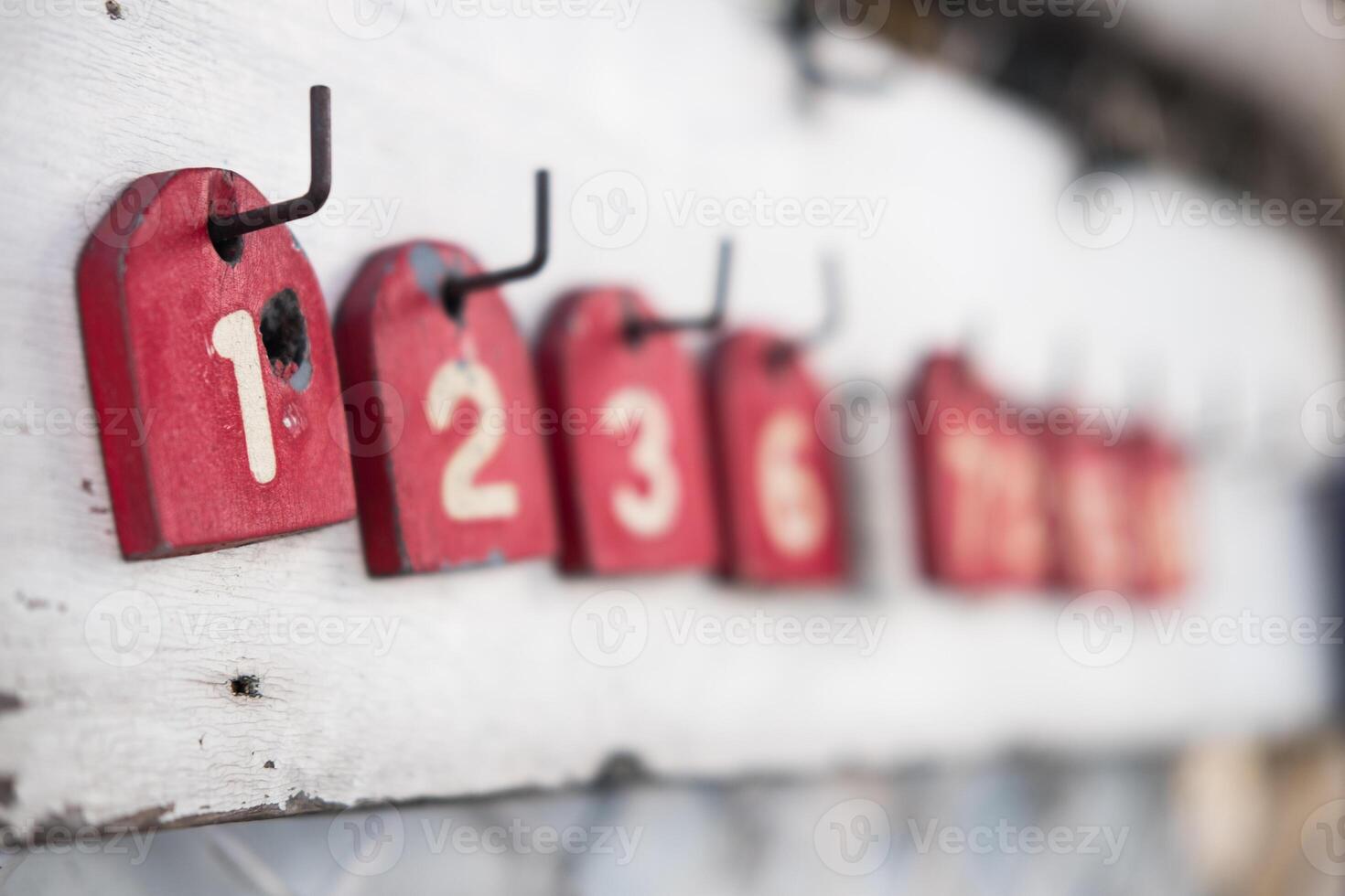 A wood red number tag for queue for motorcycle taxi drivers. Numbers for the queue photo