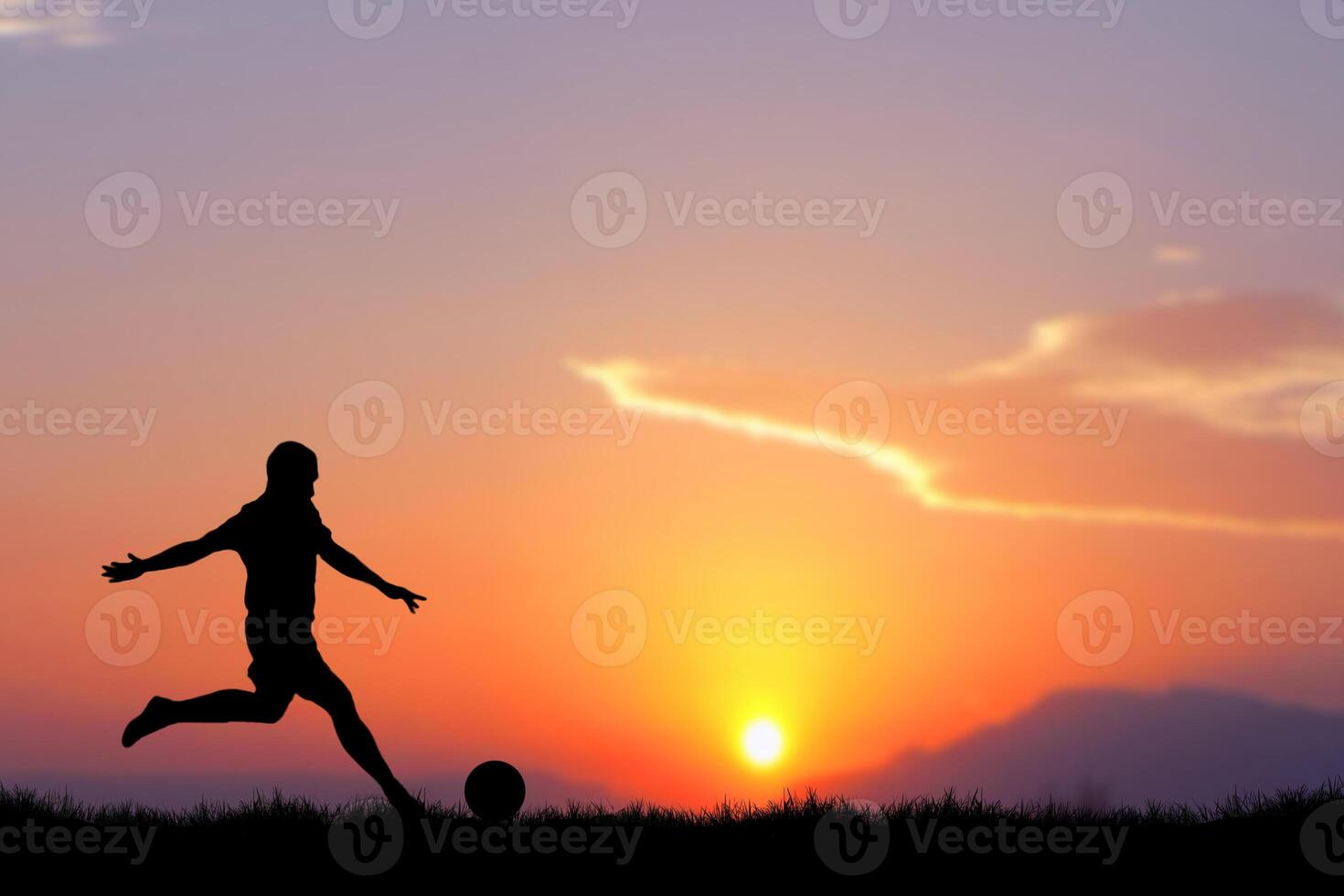 Silhouette of a Soccer Player Kicking a Ball at Sunset with Vibrant Sky in the Background photo