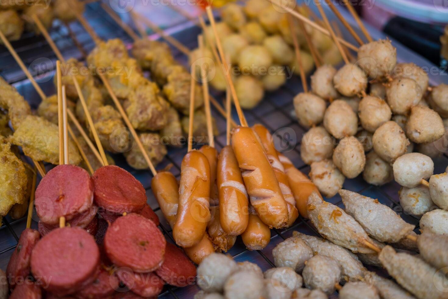Various fried skewers meatballs and sausage. Street food skewers at market in Thailand photo
