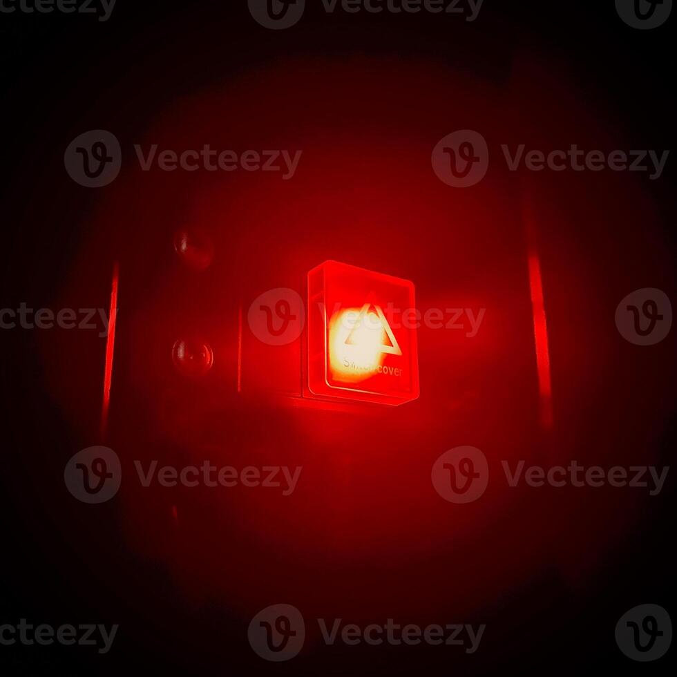 close up view of a button with bright red light shining in the dark background photo