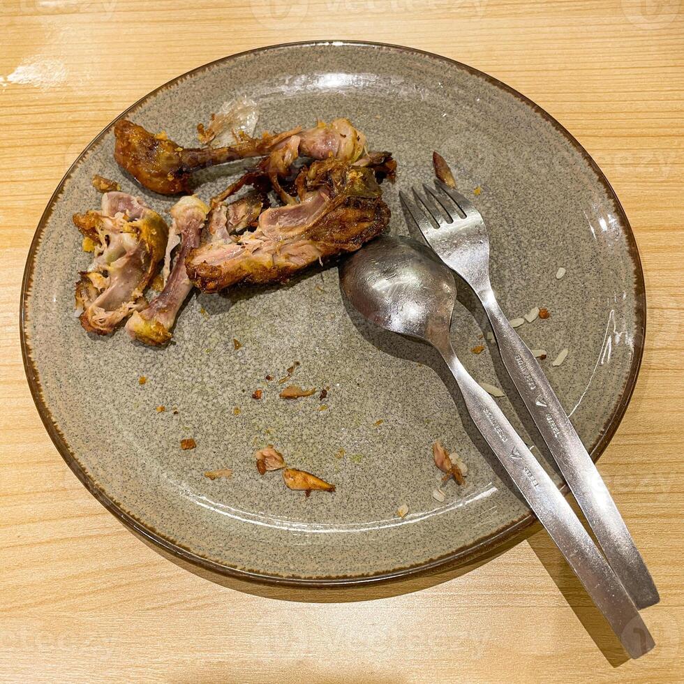 used dinner plates with spoons, forks and the remains of used chicken bones photo