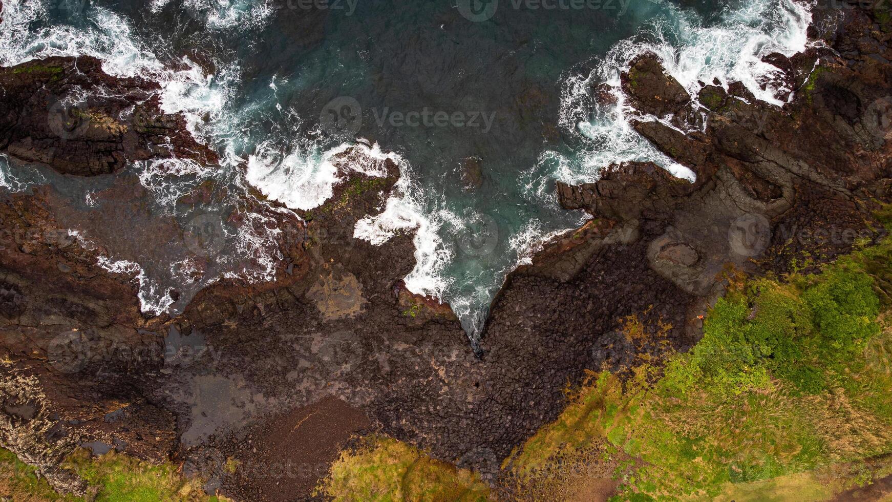Stunning drone shots of Little Blowhole, Kiama, capturing the intricate rock formations and dynamic waves from a top-down view. Perfect for showcasing Australia's coastal beauty and natural wonders. photo