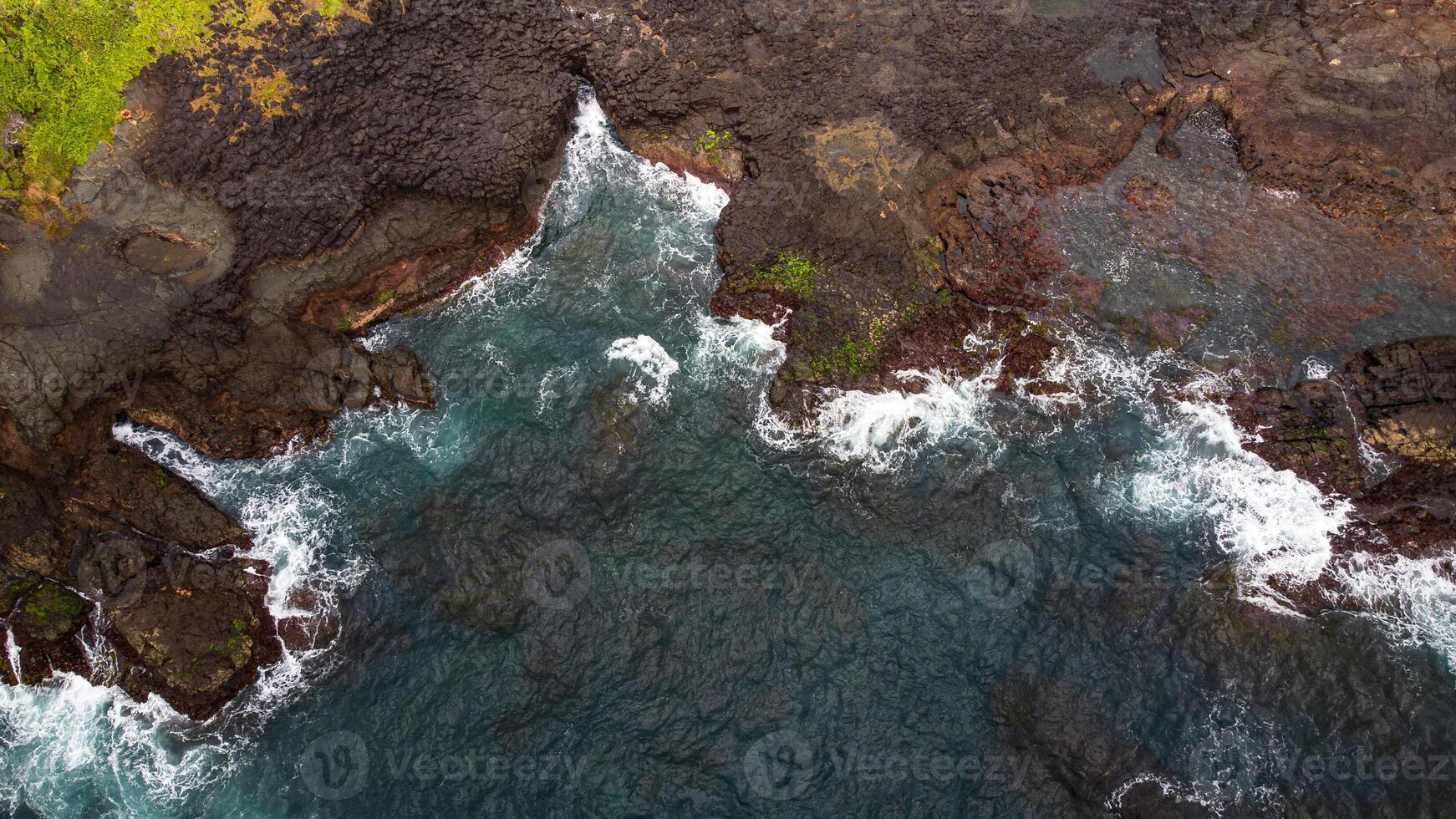 Stunning drone shots of Little Blowhole, Kiama, capturing the intricate rock formations and dynamic waves from a top-down view. Perfect for showcasing Australia's coastal beauty and natural wonders. photo