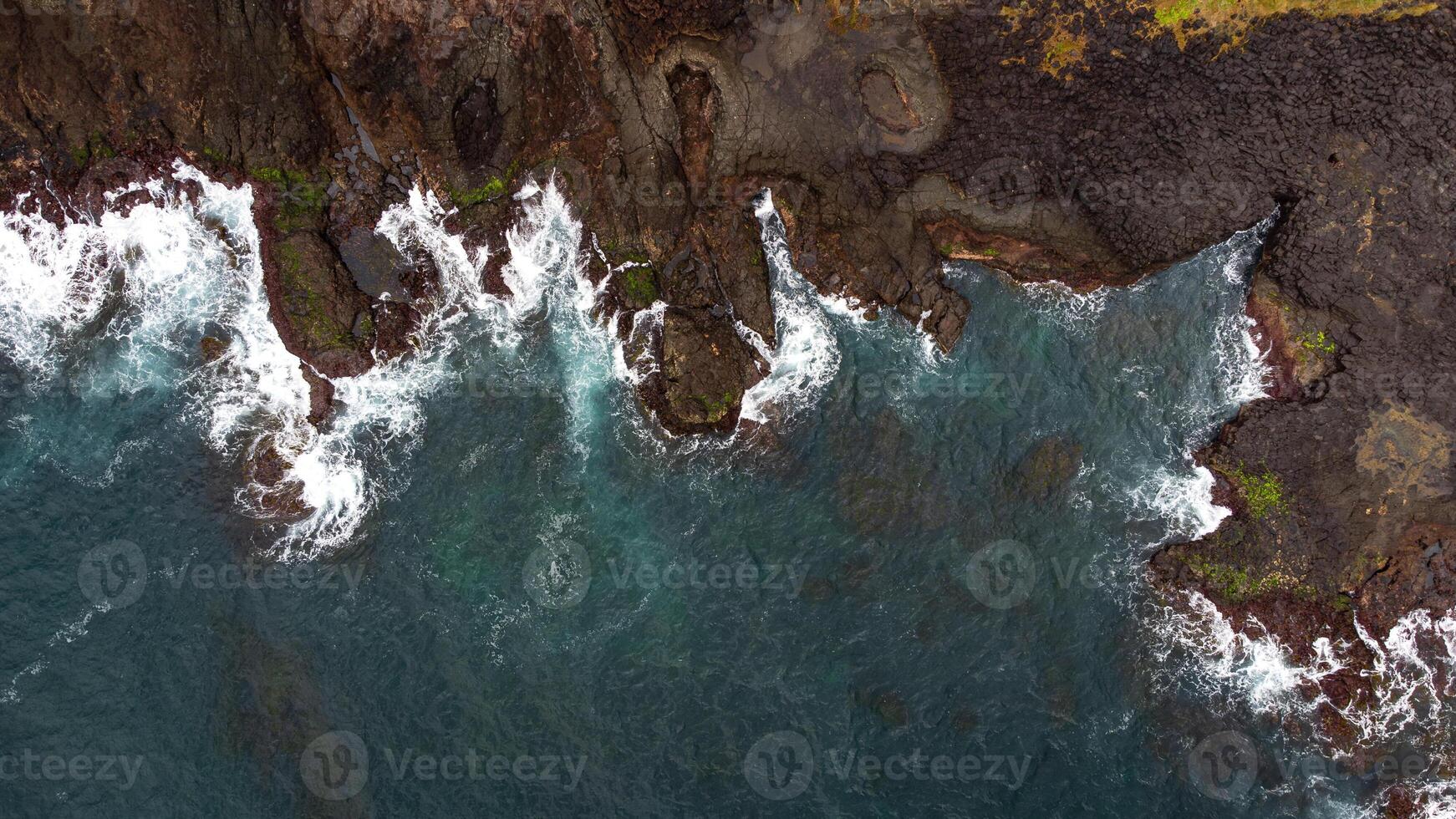 Stunning drone shots of Little Blowhole, Kiama, capturing the intricate rock formations and dynamic waves from a top-down view. Perfect for showcasing Australia's coastal beauty and natural wonders. photo
