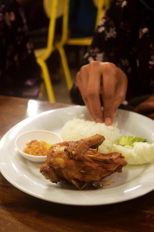 Someone's hand is about to take grilled chicken is on a wooden table photo