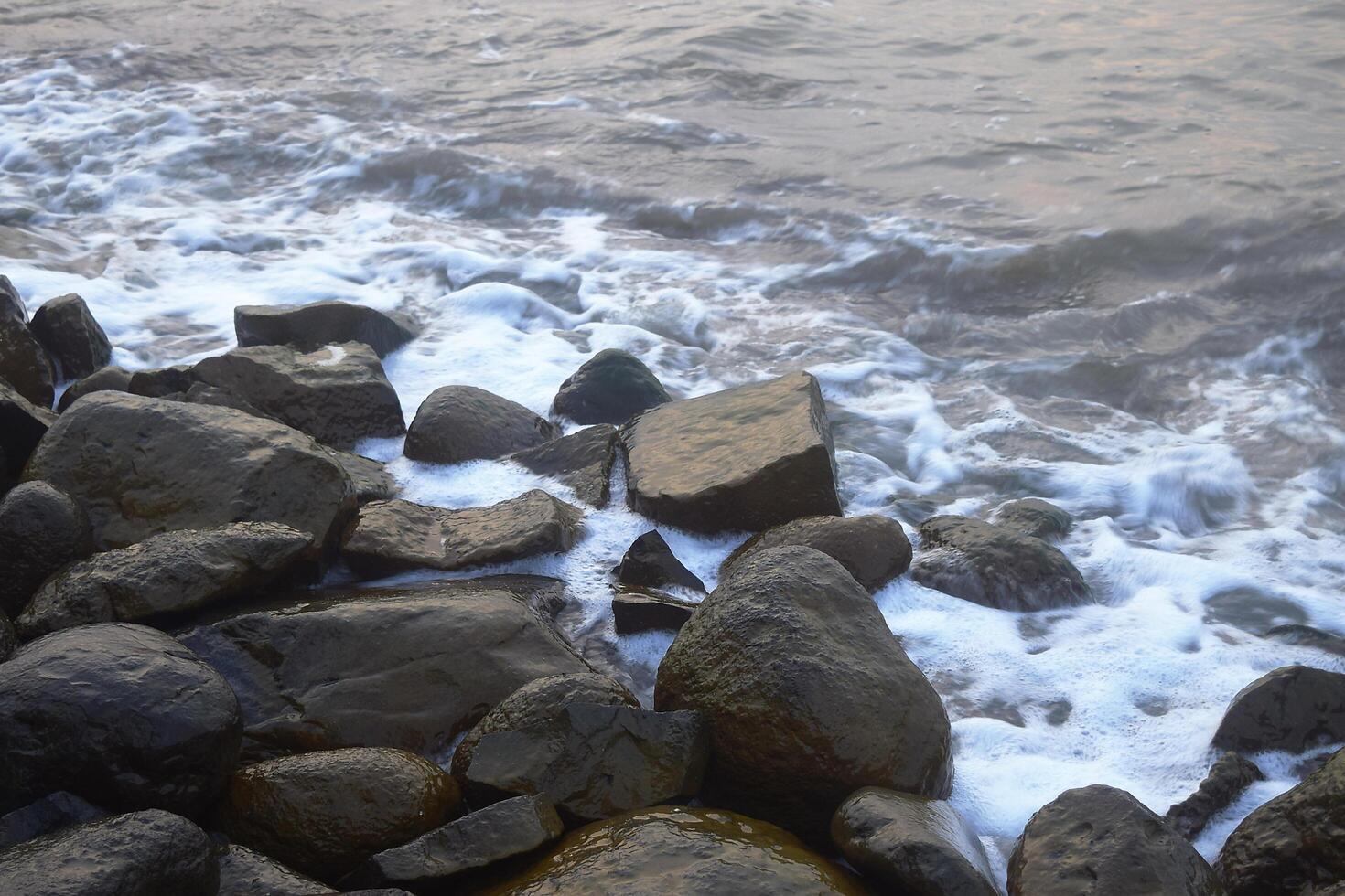Large boulders hit by the waves around the beach photo