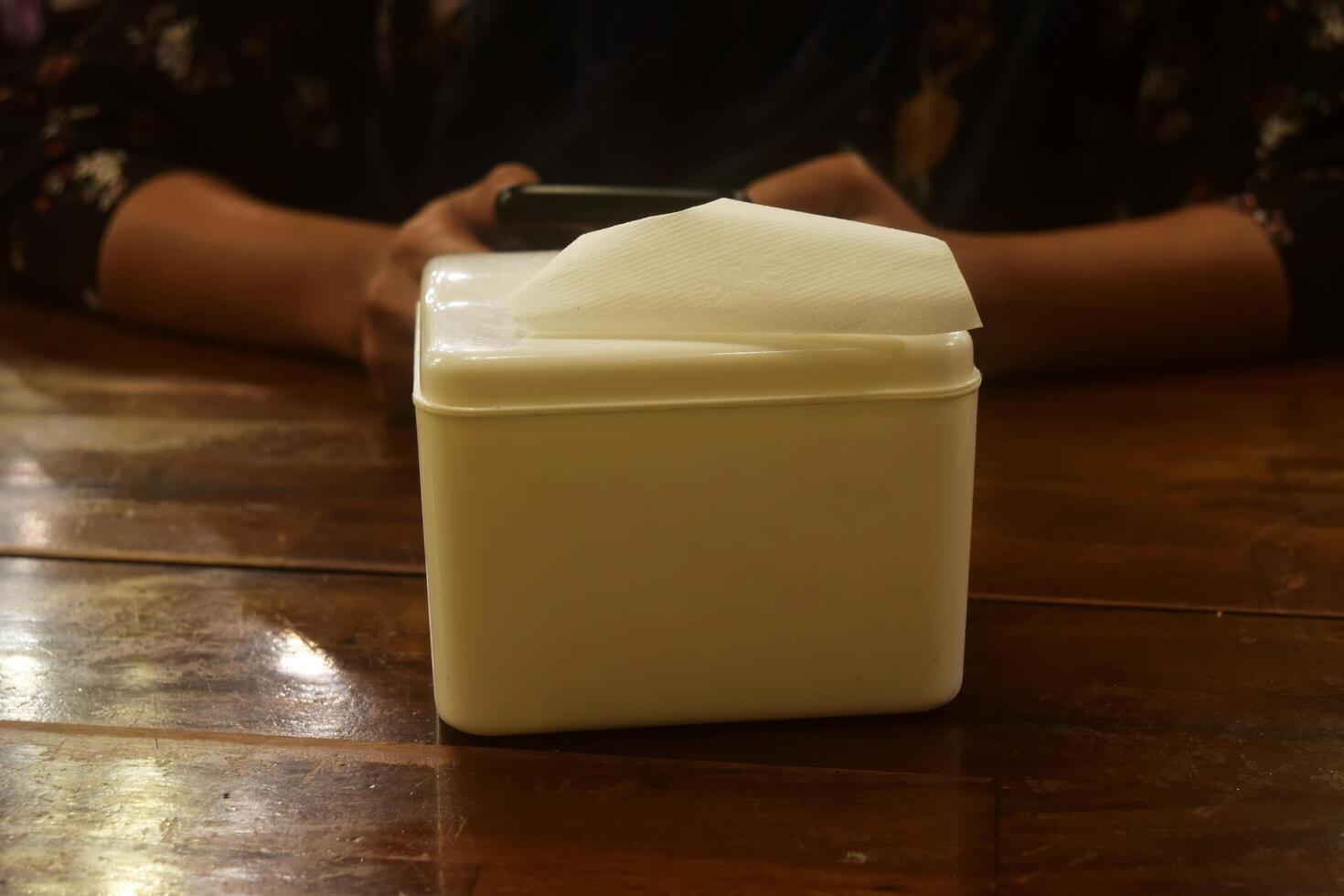 A white tissue holder is on a wooden table photo