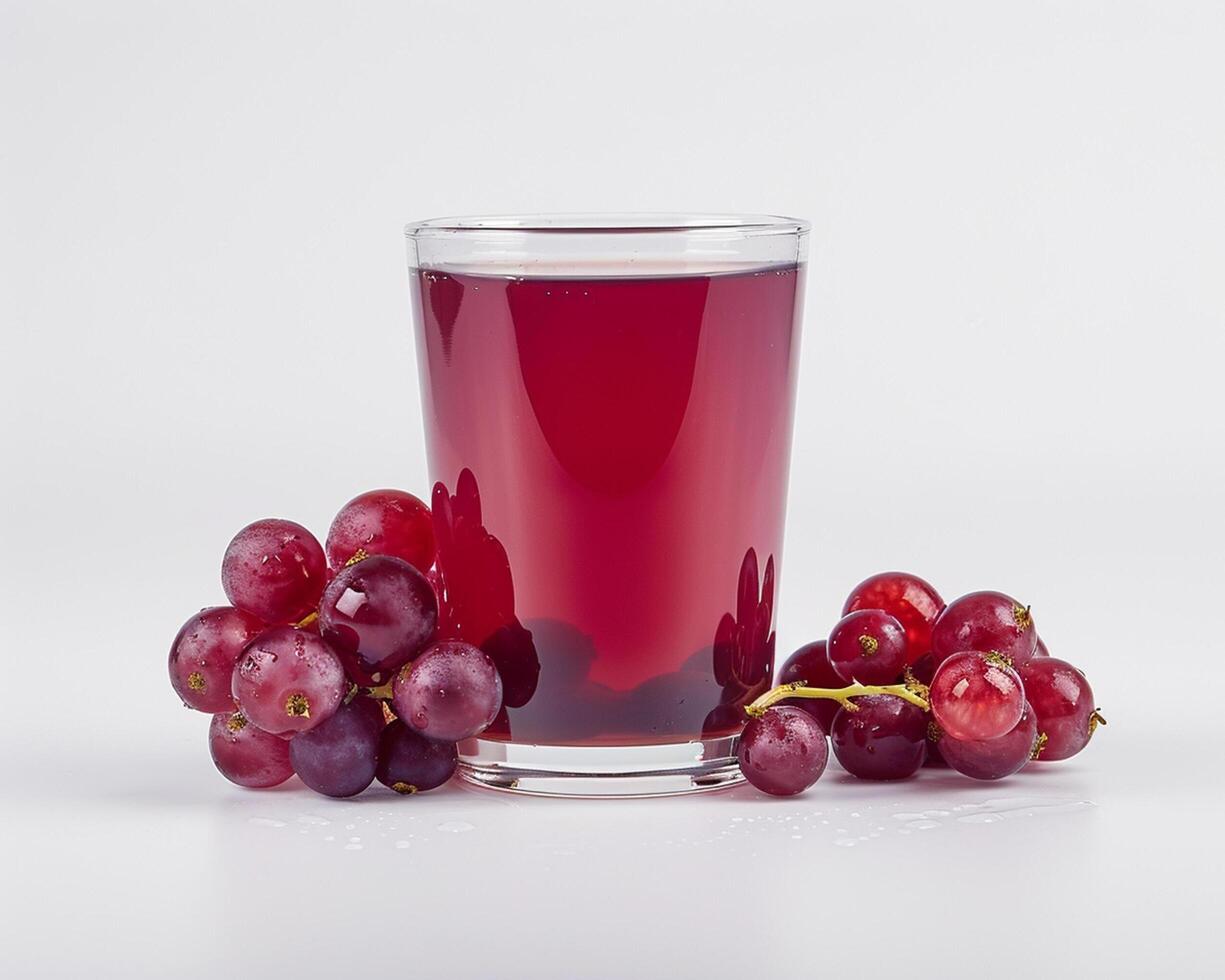 a glass of red grape juice with some grapes photo