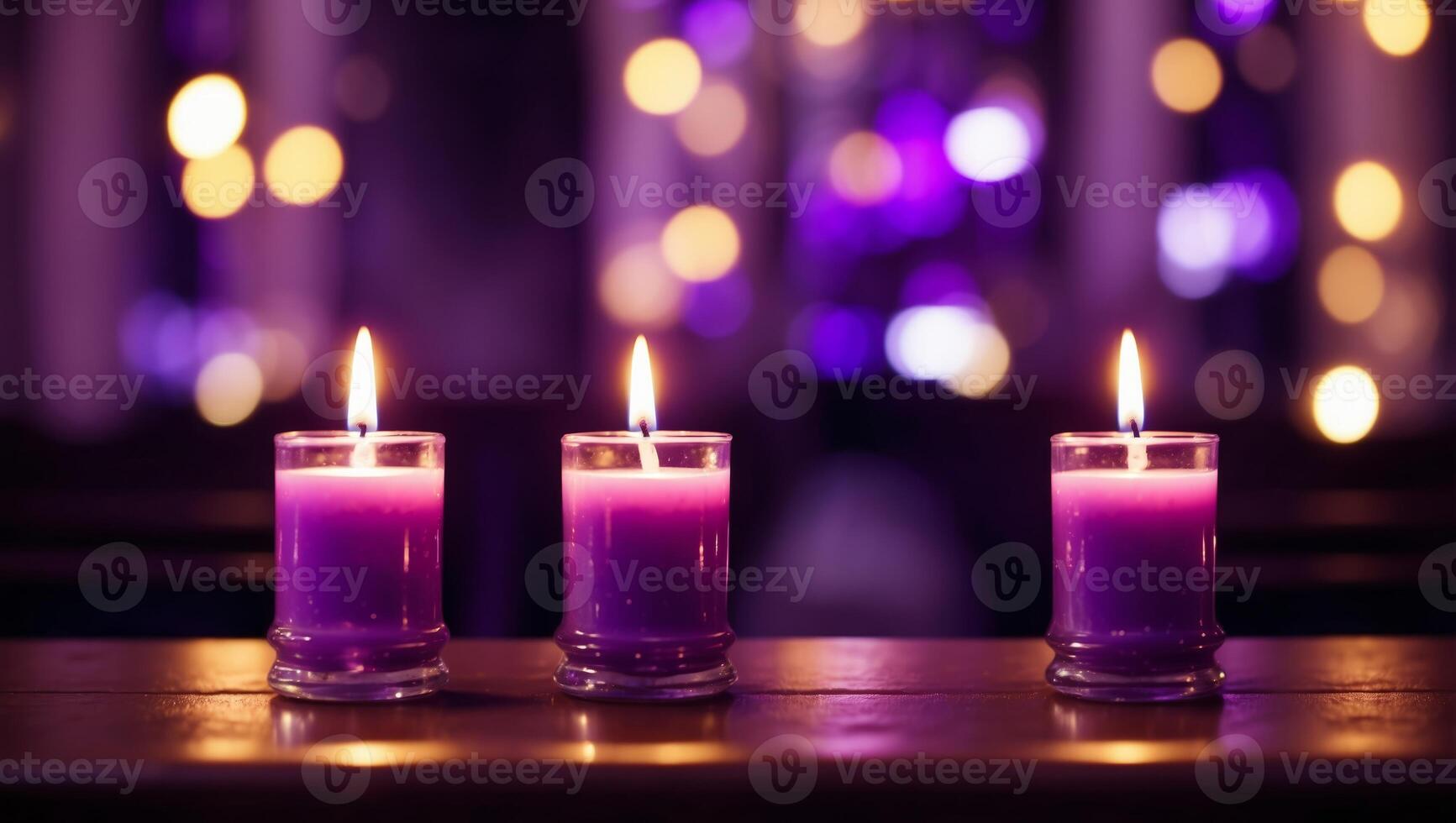 Three purple candles sit on a wooden table photo