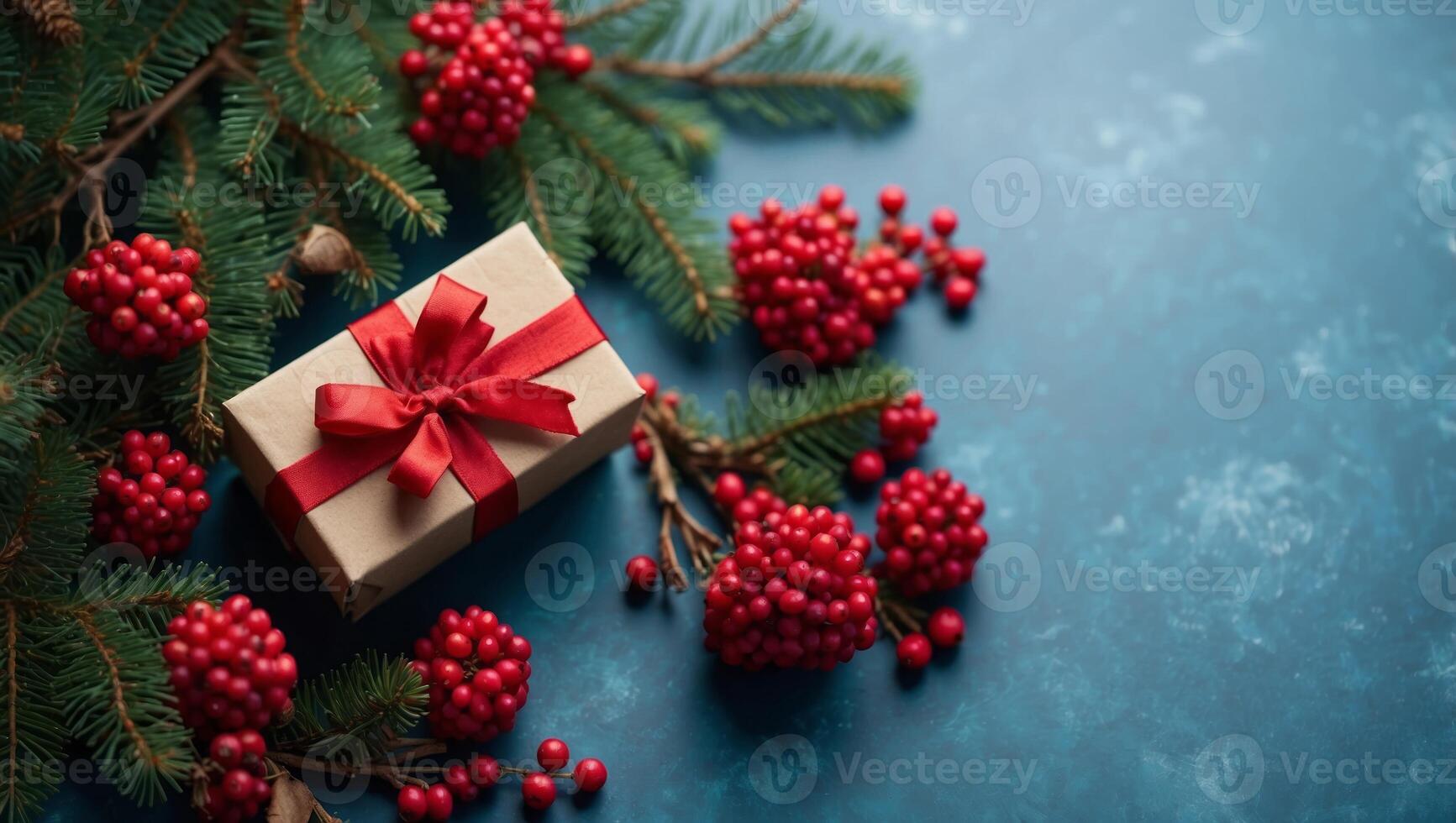 Christmas tree branch with red berries and gift box over blue xmas background Flat lay, top view, copy space Christmas banner mockup with copy space. photo