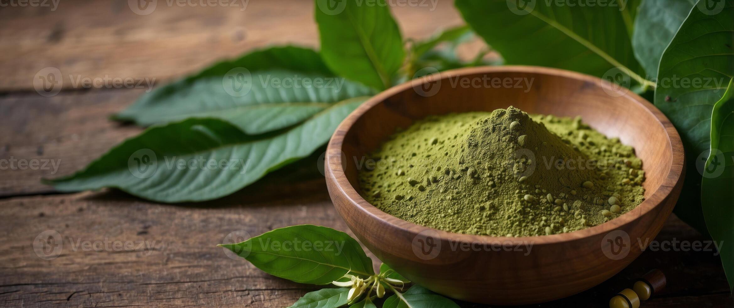 Mitragyna Speciosa Korth or kratom powder on wooden bowl wtih capsules and green leaf on rustic wooden background, top view and copy space. photo