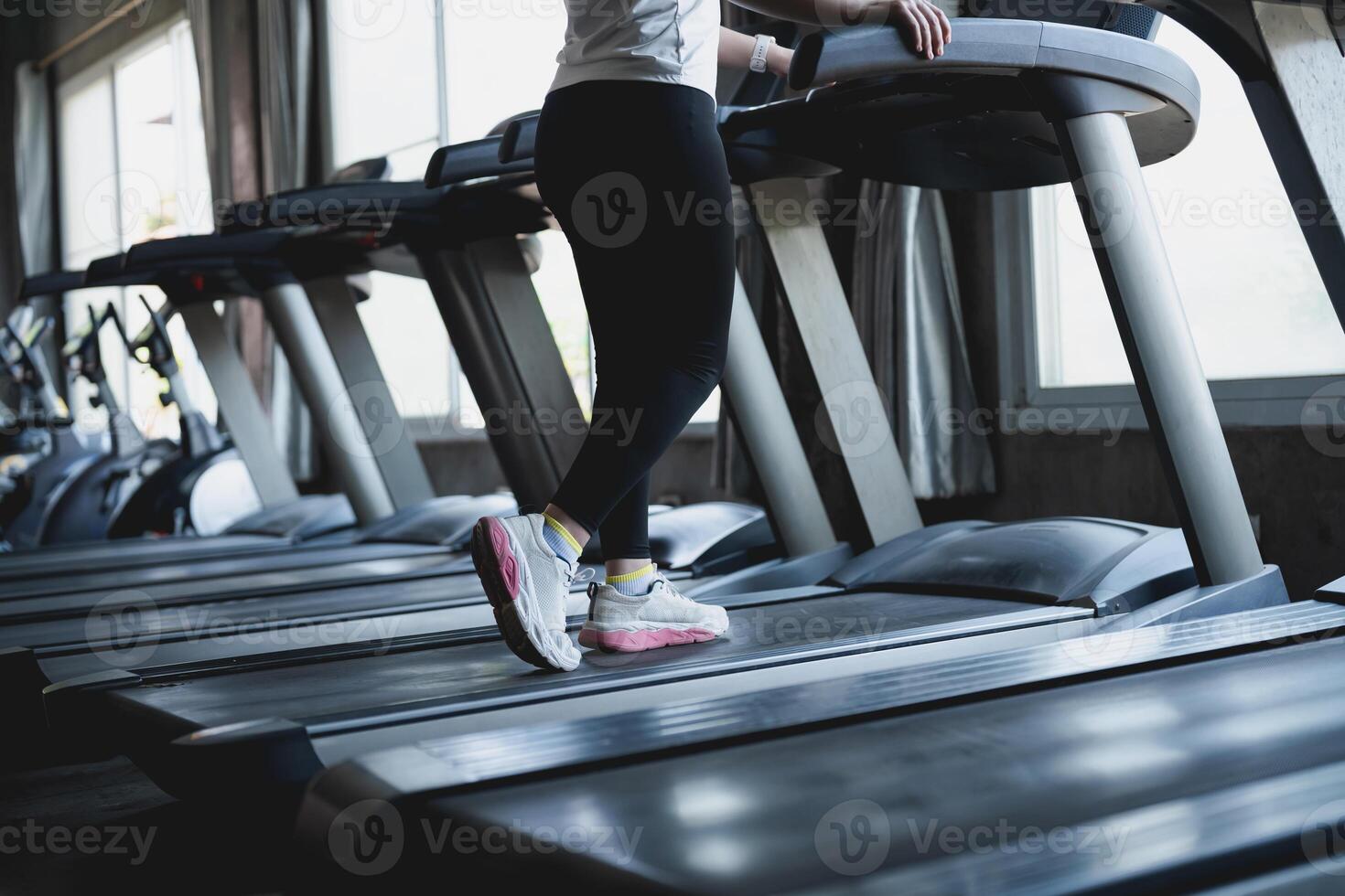 A woman is running on a treadmill in a gym photo